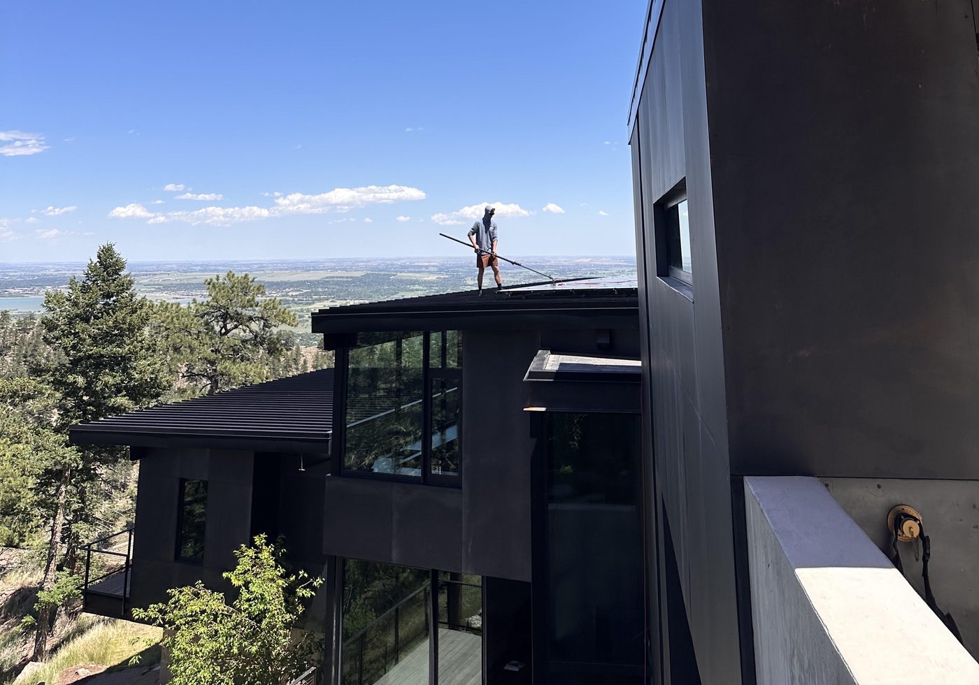 Barrett cleaning a skylight on a rooftop with a view of the Boulder valley