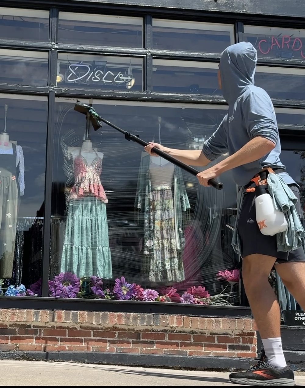 Barrett using an extension pole to clean a storefront display window